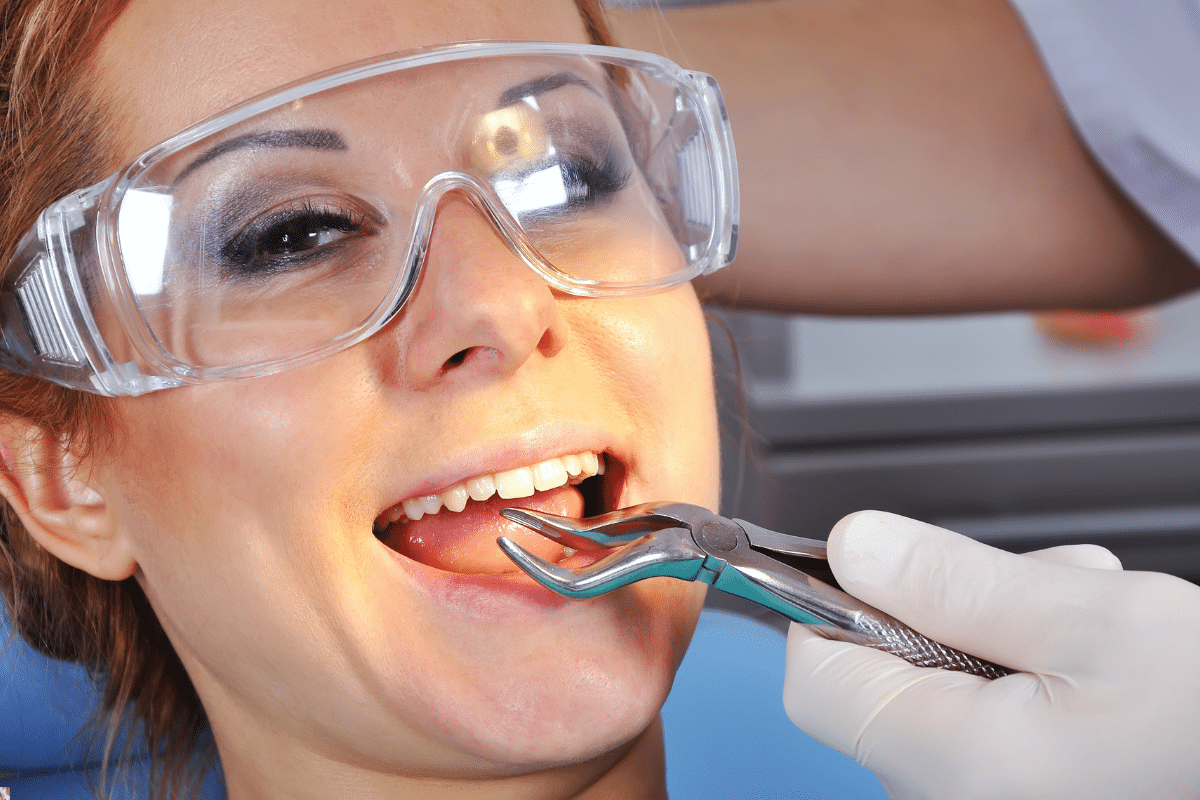 Patient receiving dental extraction with forceps during treatment at Brooklyn dental practice.