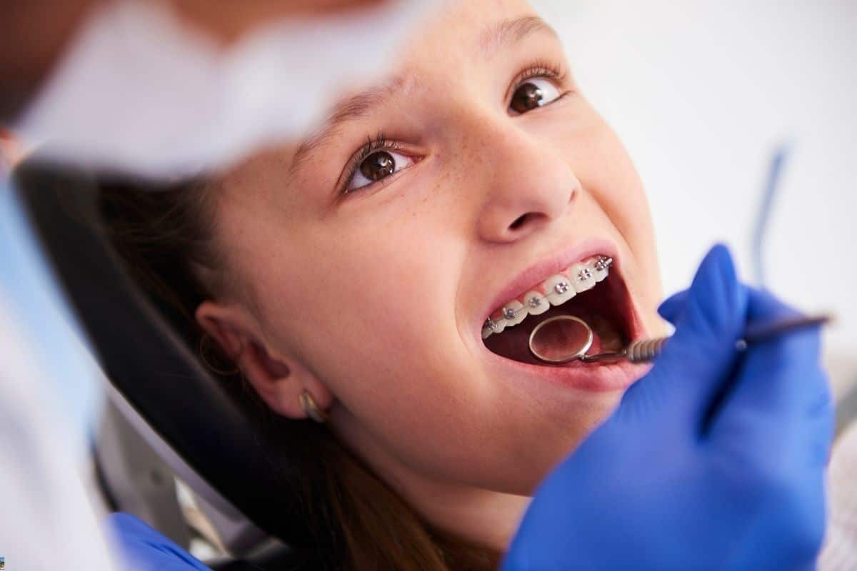 Young patient with metal braces smiling during dental examination at Brooklyn pediatric practice.