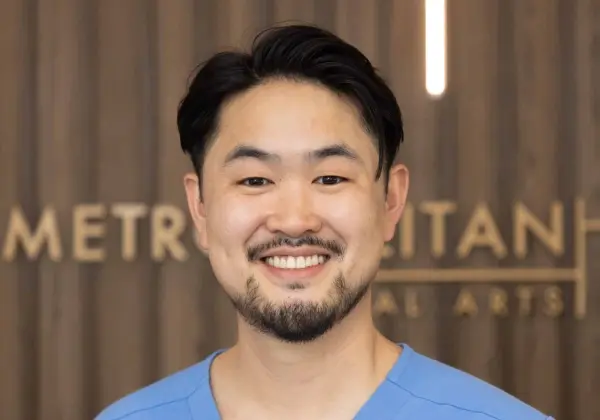 Smiling male dentist in blue scrubs at Brooklyn pediatric dental practice.