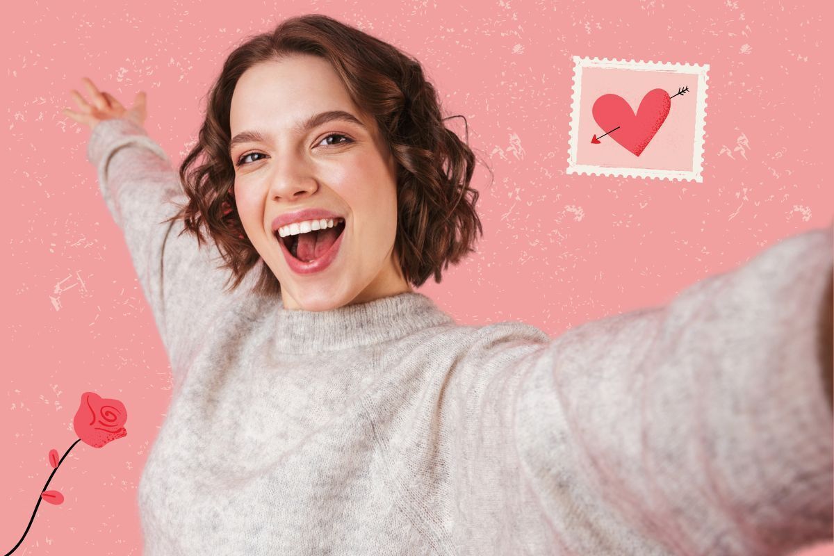 Happy young woman with bright white smile taking selfie on pink Valentine's Day background.