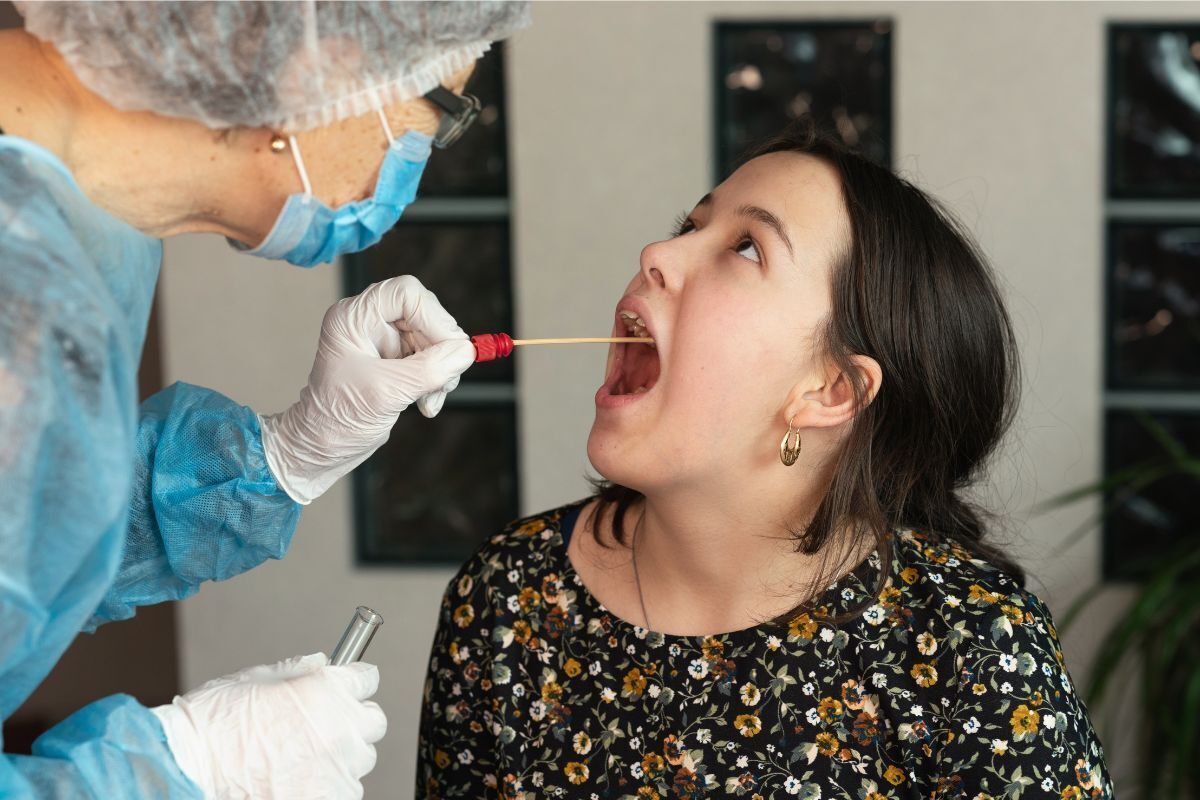 Pediatric dentist performing oral examination with swab on young patient in Brooklyn dental office.