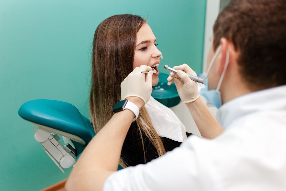 Dentist examining patient's teeth during dental checkup in Brooklyn office.