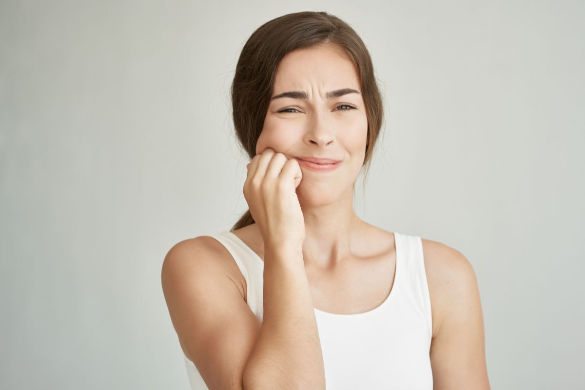 Woman with tooth pain holding her cheek, seeking dental relief in Brooklyn.