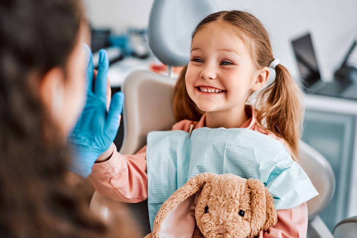 Happy child holding stuffed animal during pediatric dental visit in Brooklyn.