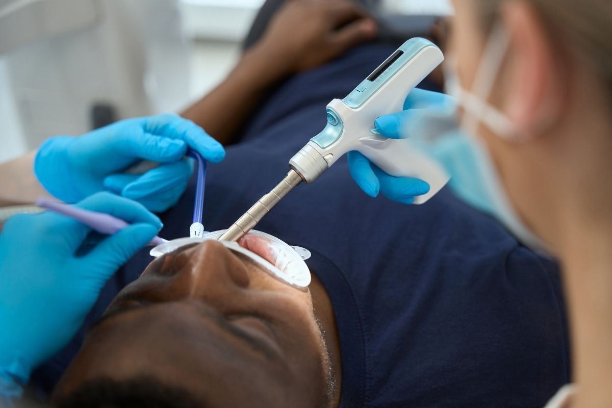 Dentist examining patient's tooth with intraoral camera during emergency dental evaluation.