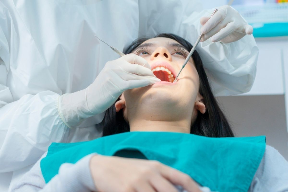 Dentist examining patient's teeth during dental checkup in Brooklyn office.