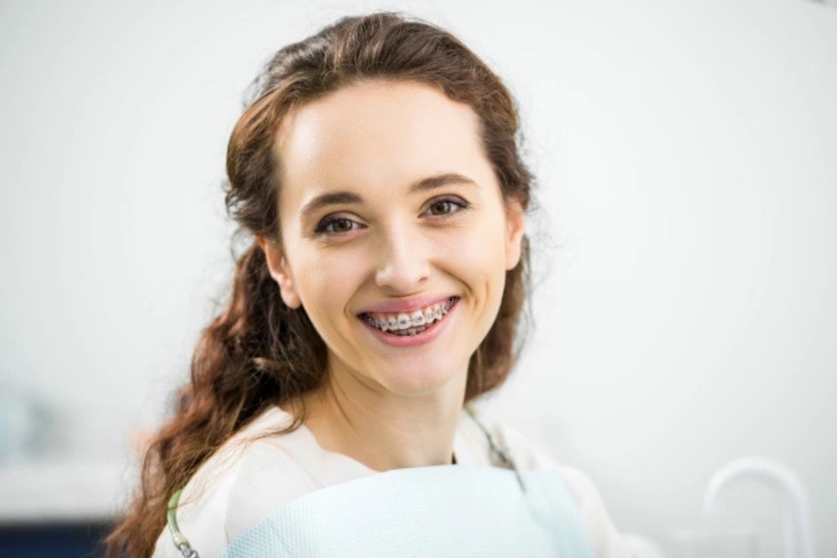 Young woman with dental braces smiling confidently at orthodontic practice in Brooklyn.