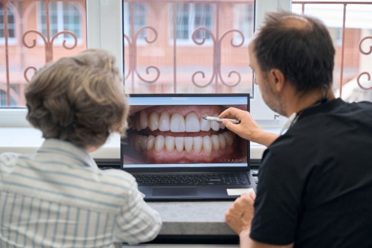 Dentist pointing to digital scan of patient's teeth during preventive care consultation in Brooklyn office.