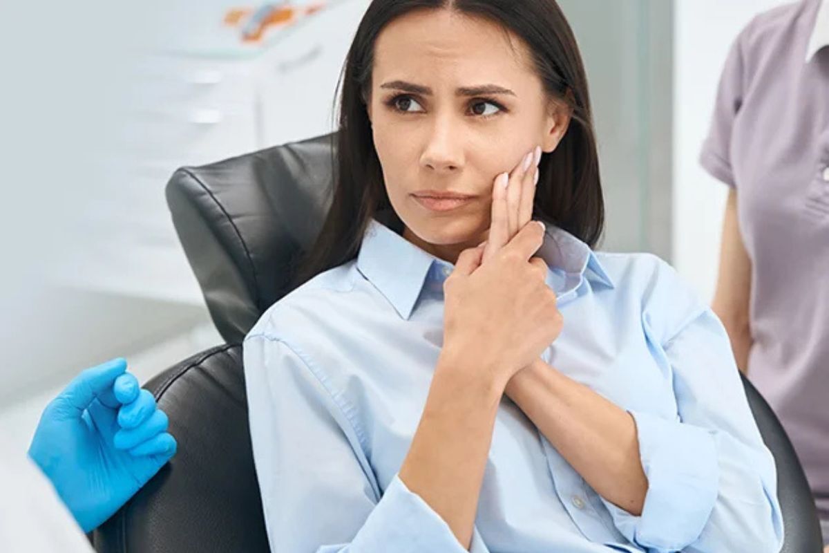 Woman in dental chair discussing tooth extraction aftercare with dentist in Brooklyn.