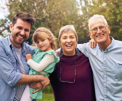 Happy multi-generational family smiling outdoors in Brooklyn.