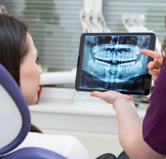 Dentist reviewing a digital dental X-ray and CT scan on a computer
