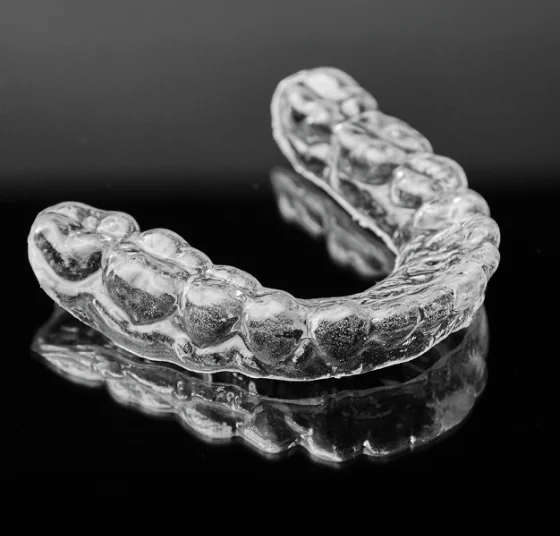 Clear dental night guard shown on a dark background