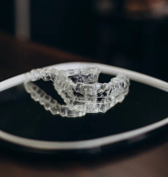 Clear dental aligner shown on a dark background