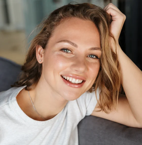 Smiling woman touching her hair while looking at the camera