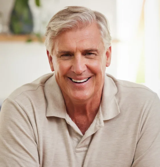 Older man smiling while wearing a beige shirt