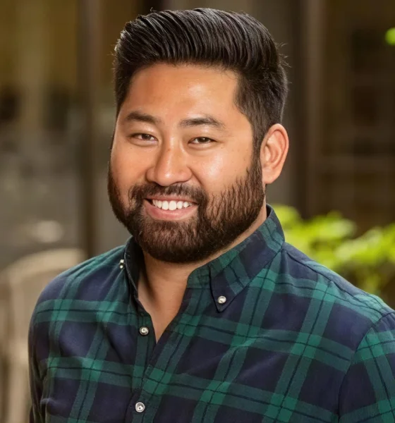 Professional headshot of a man wearing a green plaid shirt