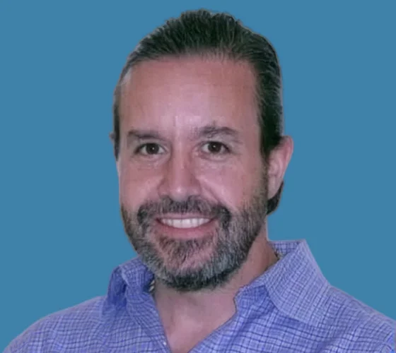 Professional headshot of a male dental professional with short dark hair and beard