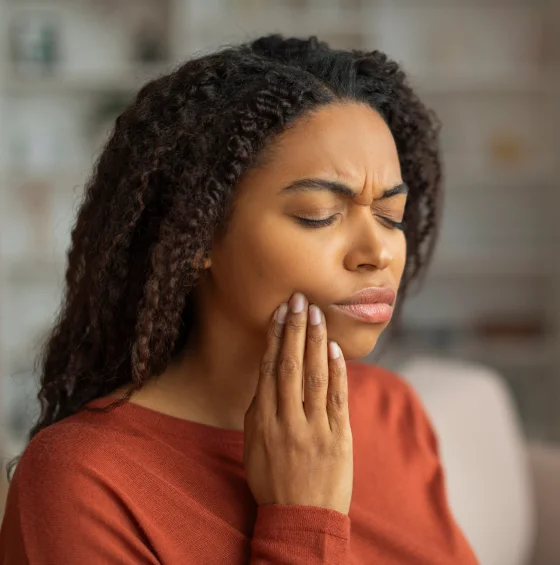 Woman holding her cheek while experiencing dental pain
