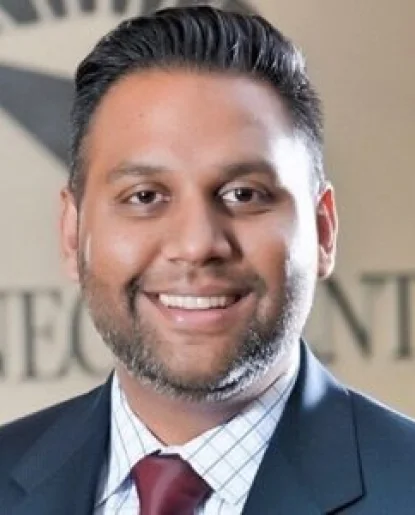 Professional headshot of a man wearing a dark suit jacket and white shirt