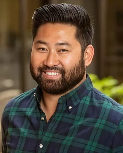 Professional headshot of a man wearing a green plaid shirt