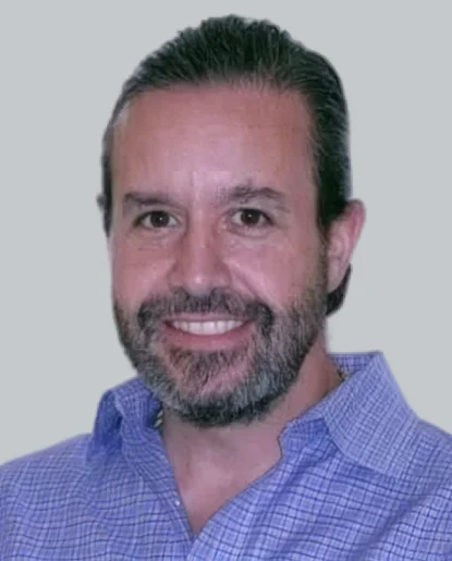 Professional headshot of a man with a beard wearing a light blue shirt