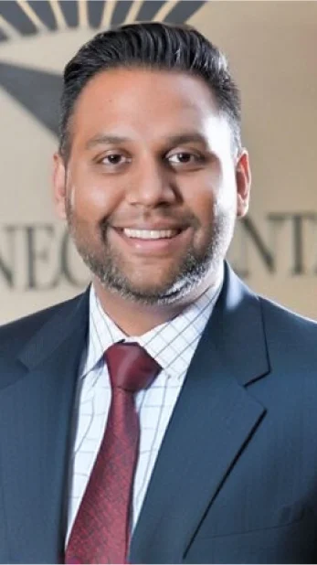 Professional headshot of a man wearing a dark suit jacket and white shirt