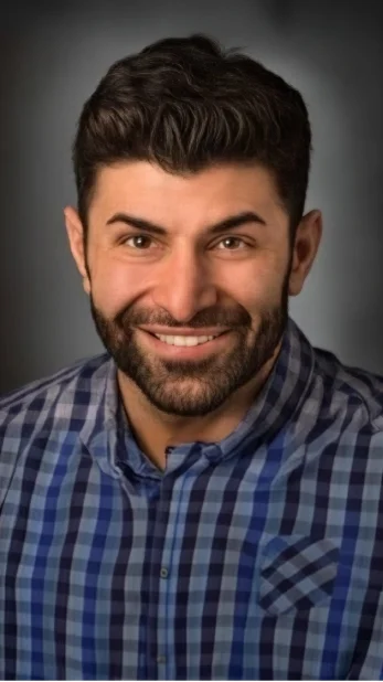 Professional headshot of a man with a beard wearing a dark shirt