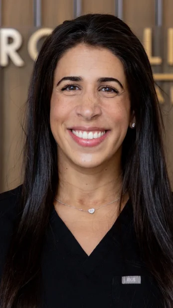 Professional headshot of a smiling female dental professional with long dark hair
