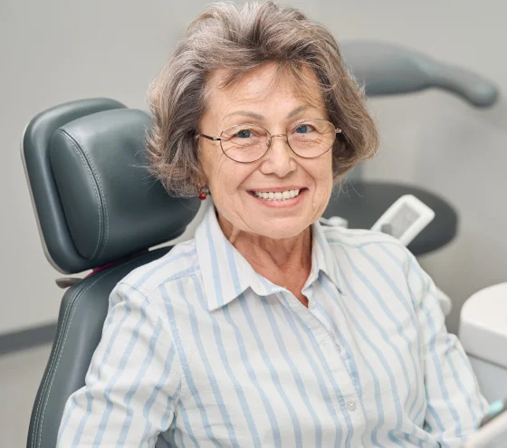 Older woman smiling while seated in a dental treatment chair