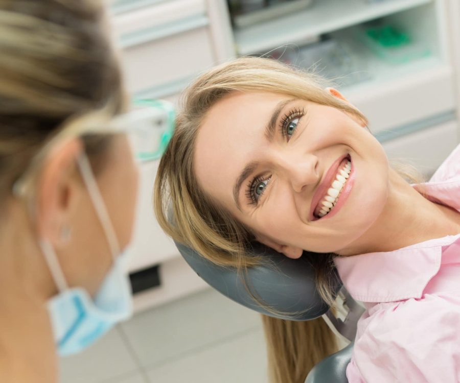 Horizontal color close-up headshot of beautiful woman having dental examination and sincerely smiling at dentist.